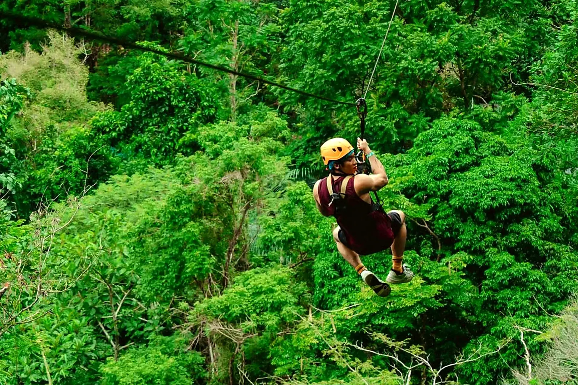 Rider crossing the jungle canopy on a Hawk Adventure zipline in Koh Samui