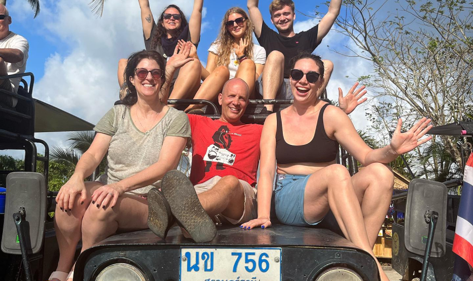 Joyful group of friends raising their hands in excitement on a private Jeep safari in Samui