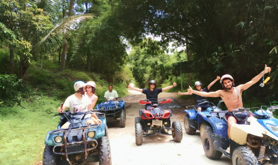 Group of friends enjoying a private ATV tour on a dirt road amidst the lush greenery of Samui's jungle