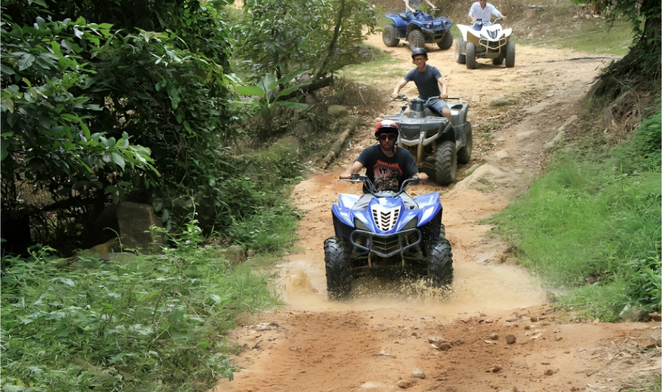 Adventurous riders splash through a muddy puddle on an ATV during a Samui excursion